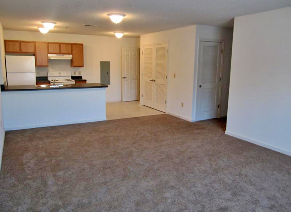 an empty living room with a kitchen and