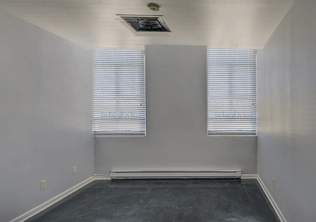 A room with a black floor and white walls with two windows.