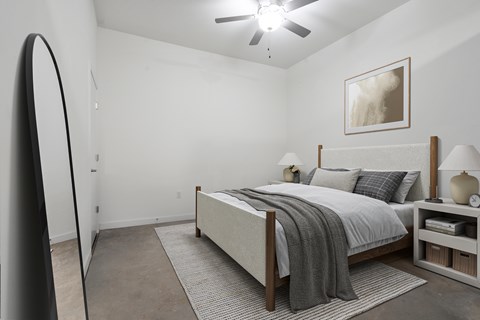 A bedroom with a bed, nightstand, and a painting on the wall.