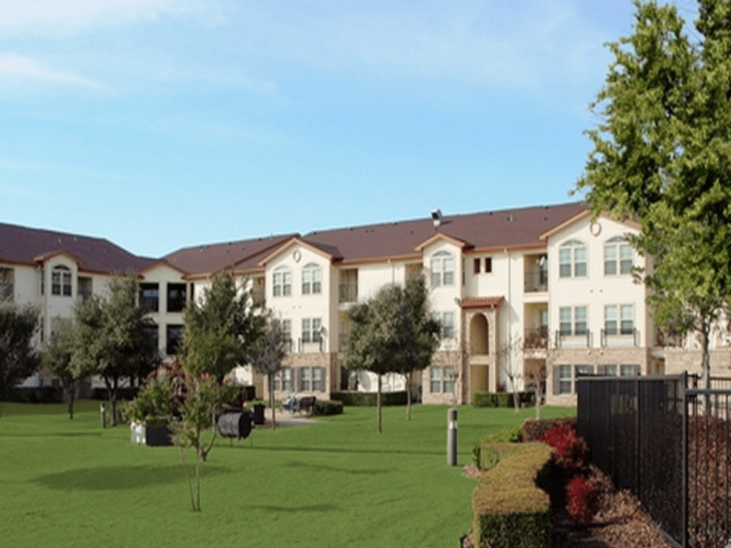 an exterior view of an apartment building on a green lawn