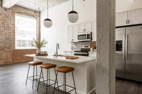 A kitchen with a white countertop and stools.