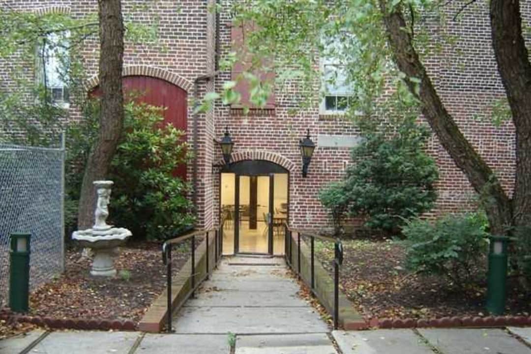 the entrance to a brick building with trees and a sidewalk