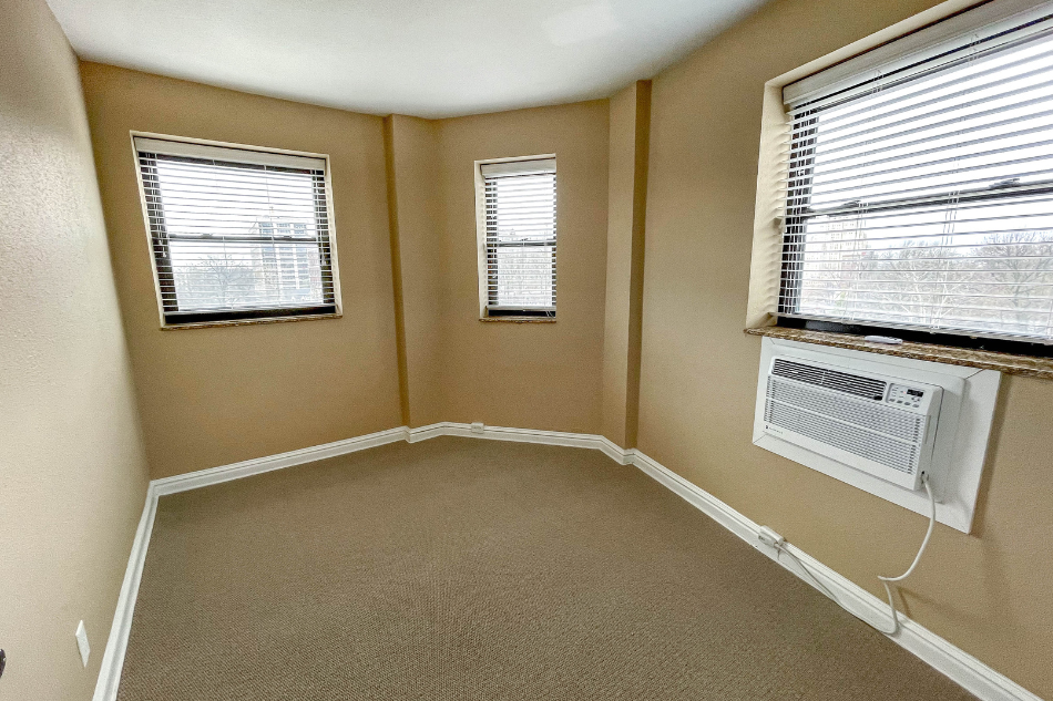 an empty room with two windows and a radiator