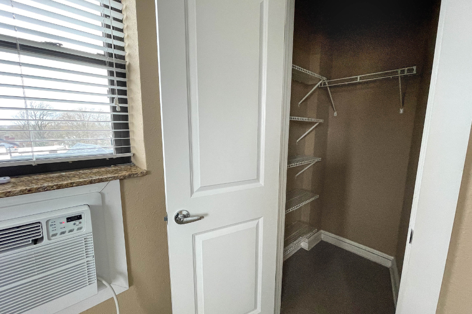 a walk in closet with a white door and a window