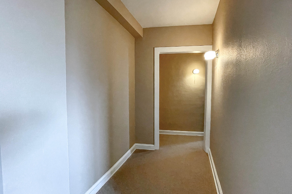 an empty hallway with a door to a closet and a lamp on the wall
