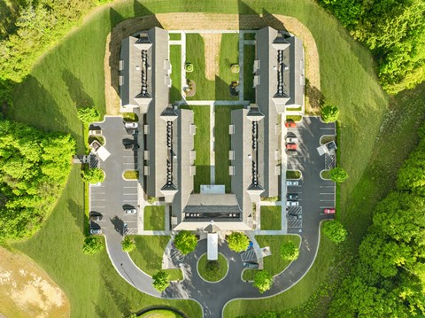 An aerial view of a parking lot with a building in the background.