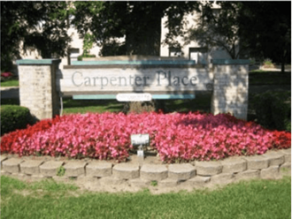 a sign for campenture place in front of a bed of pink flowers