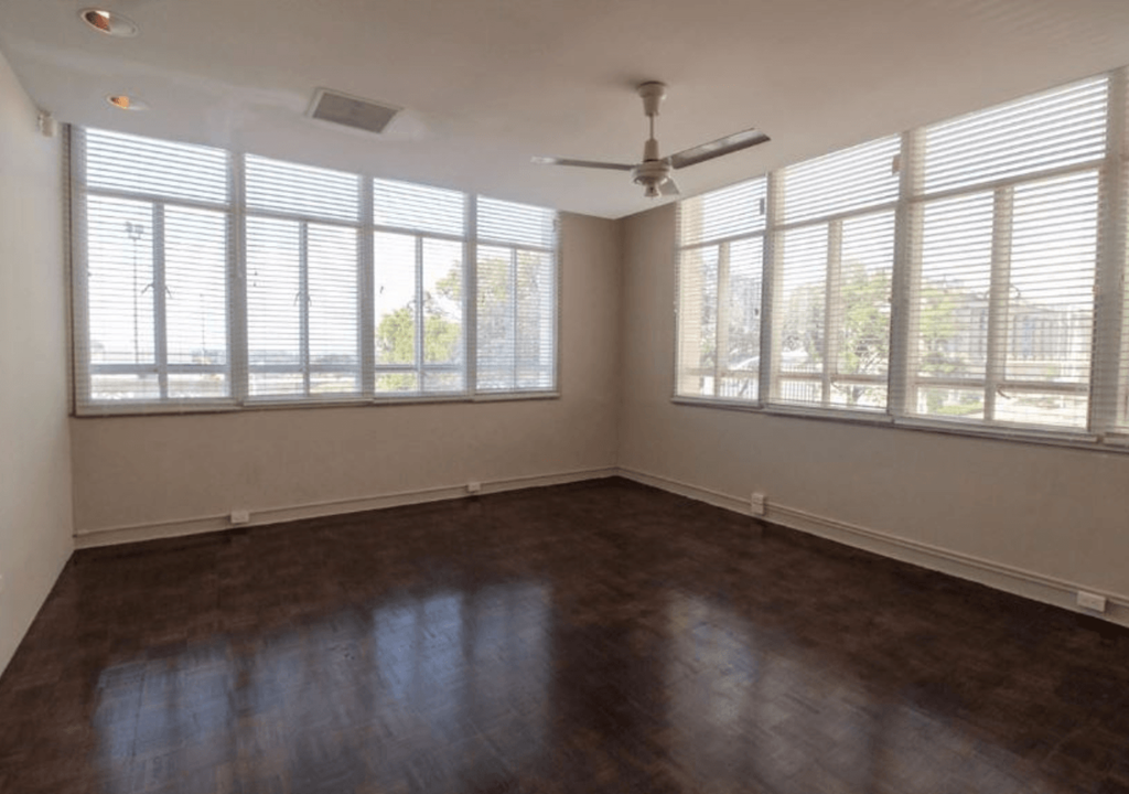 A room with a ceiling fan and large windows.
