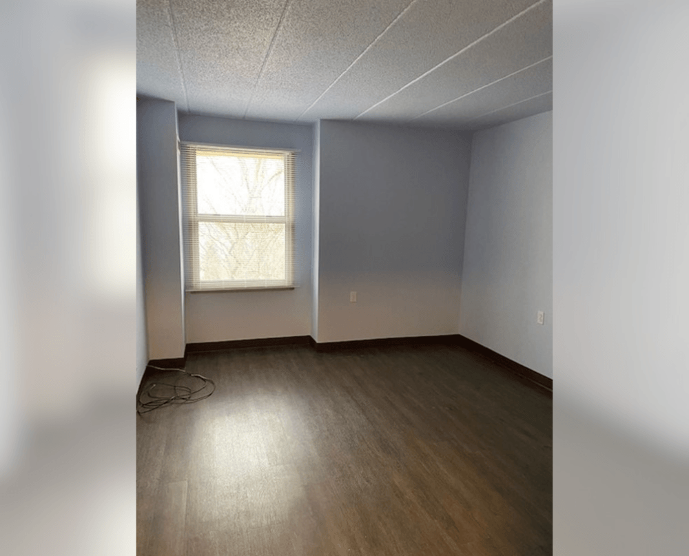 an empty room with wood floors and a window