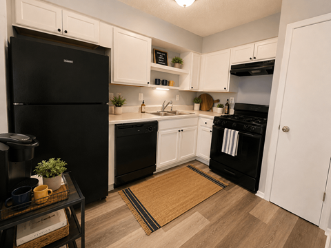 A black fridge and oven in a kitchen with white cabinets.