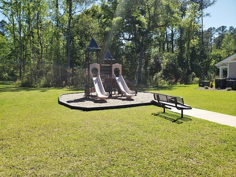 A playground with a slide and a bench in the foreground.