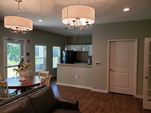 A brown leather couch sits in a living room with a dining table and chairs.