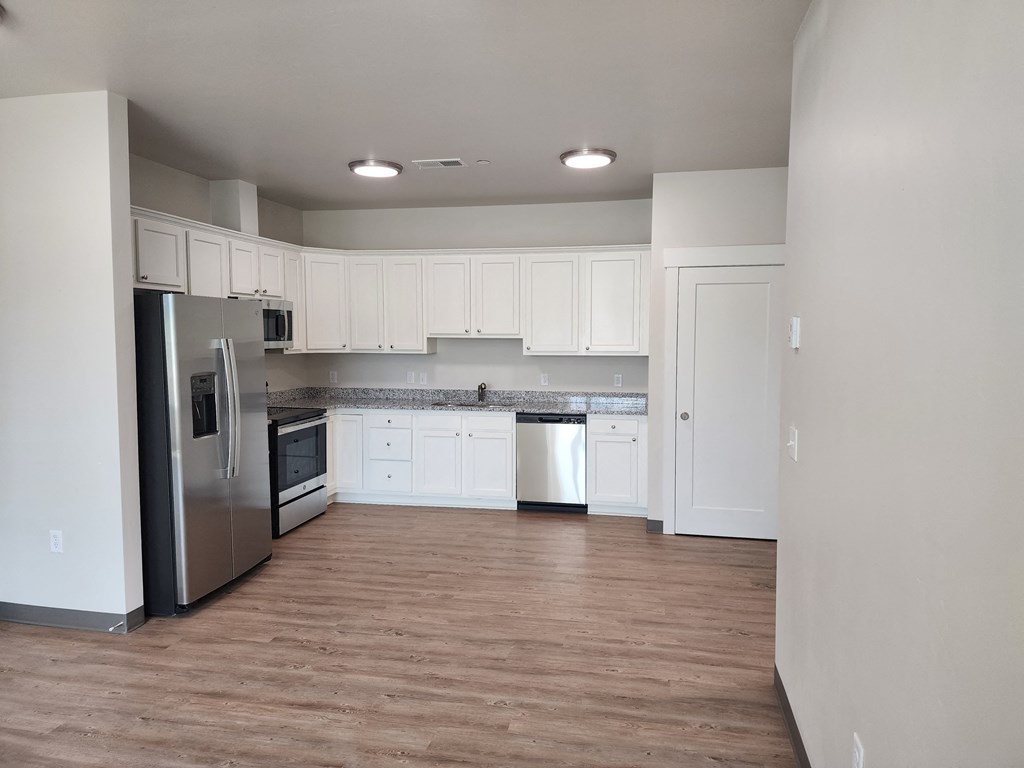 an empty kitchen with white cabinets and stainless steel appliances