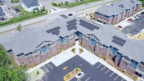 A parking lot in front of a building with solar panels on the roof.