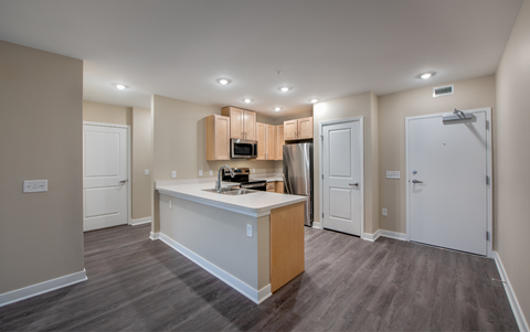 an empty kitchen with an island and a stainless steel refrigerator