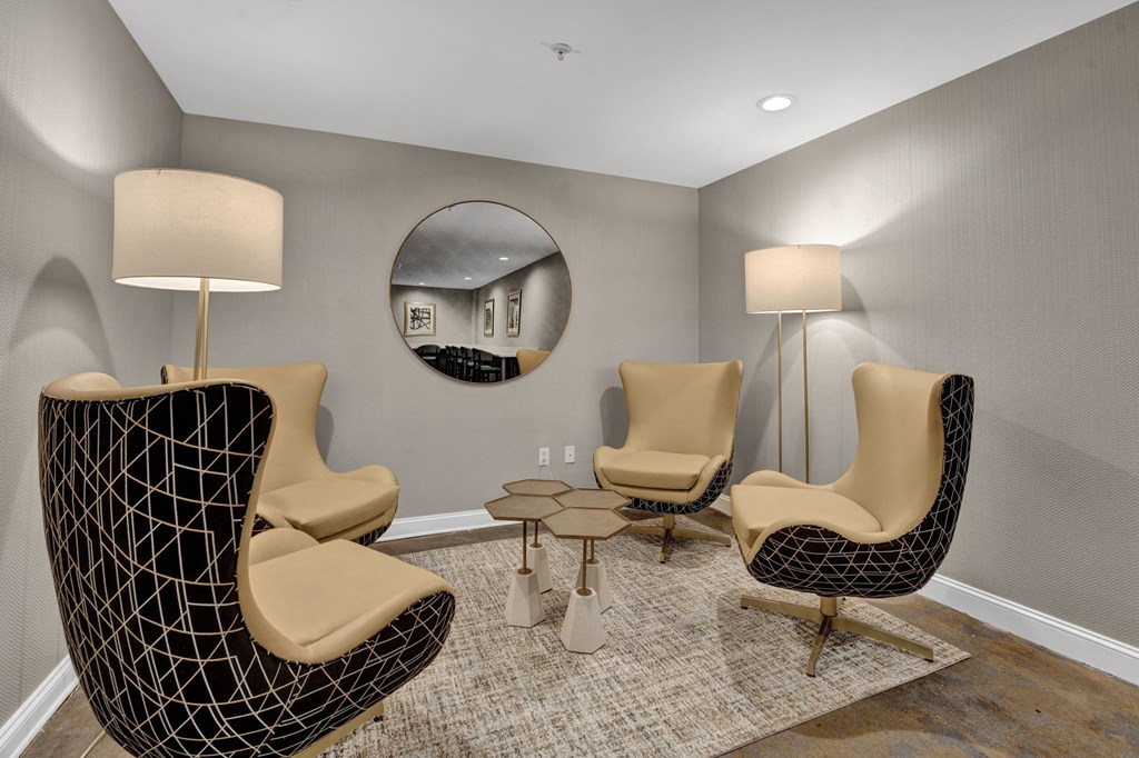 A living room with a black chair and a round mirror on the wall.