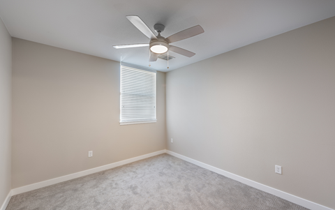 an empty room with a ceiling fan and a window