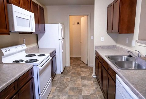 A kitchen with white appliances and brown cabinets.