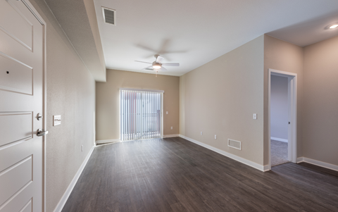 an empty living room with wood floors and a ceiling fan