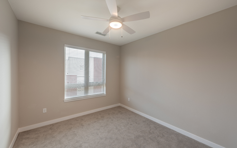 an empty bedroom with a ceiling fan and a window