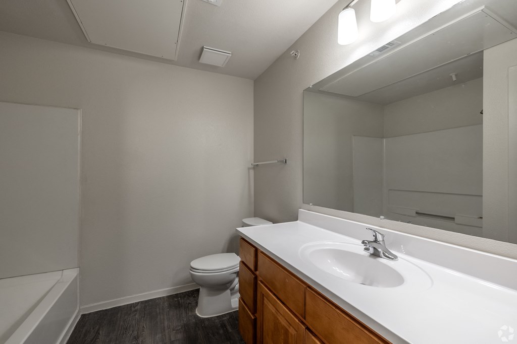 A white bathroom with a toilet, sink, and mirror.