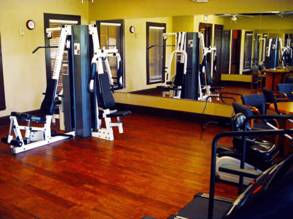 a gym with weights and cardio equipment on a wooden floor