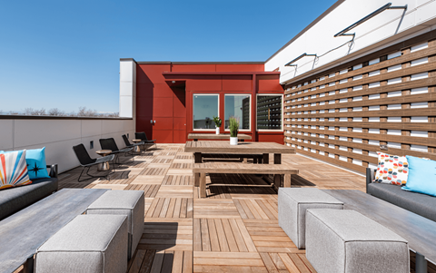 a roof deck with furniture and a red building in the background