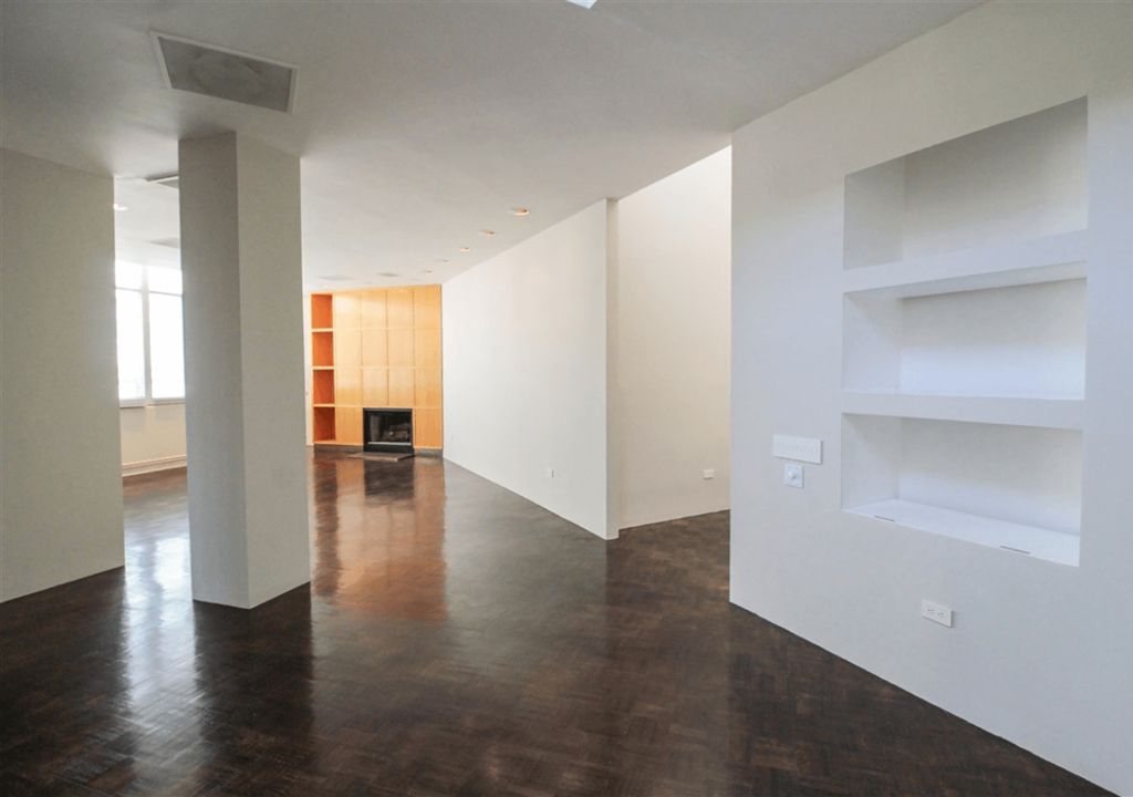 A room with white walls and a fireplace with a wooden mantle.
