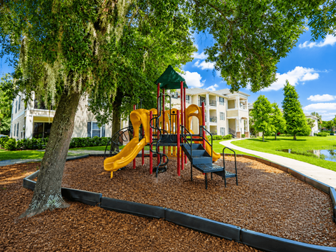 A playground with a yellow slide and a green canopy.
