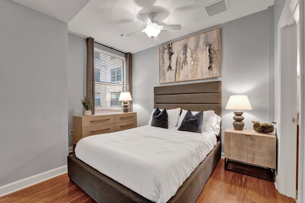 A bedroom with a large bed, two nightstands, and a ceiling fan.
