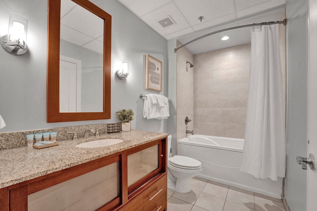 A bathroom with a toilet, sink, and mirror.