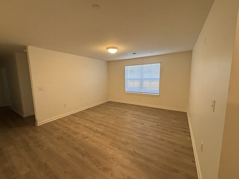 A room with wooden flooring and a window with blinds.