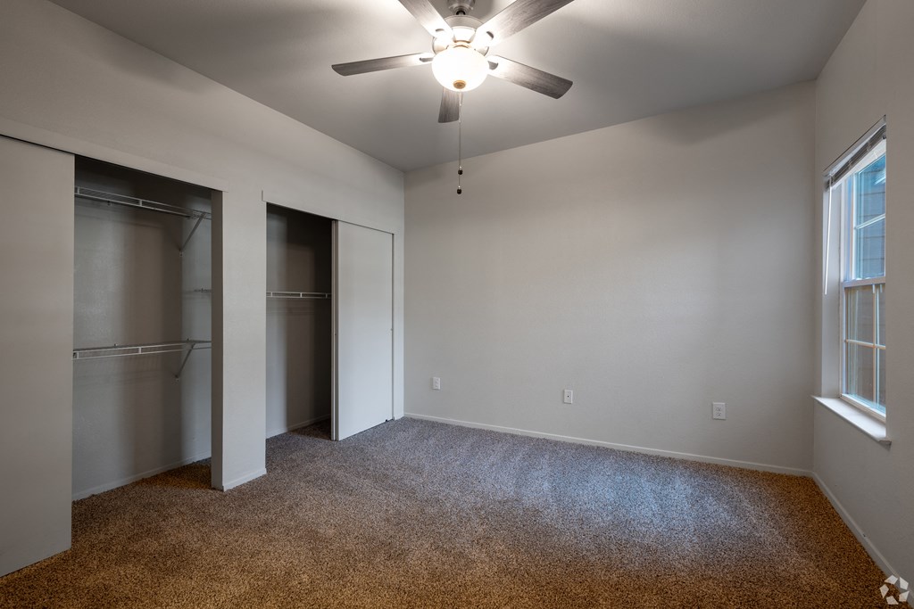 A room with a ceiling fan and carpeted floor.
