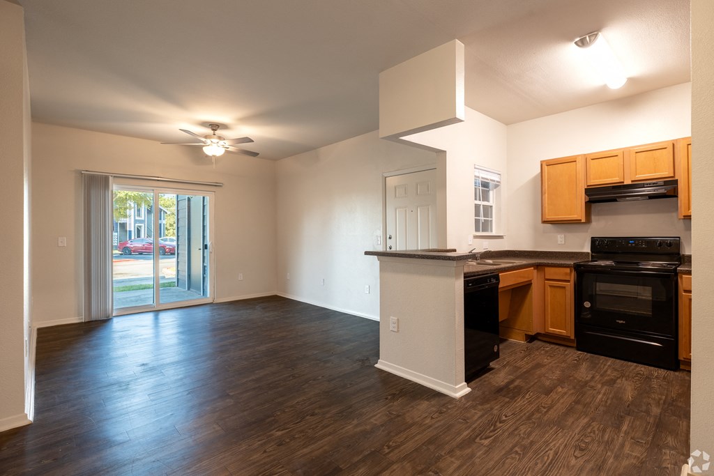 A kitchen with wooden floors and black appliances.
