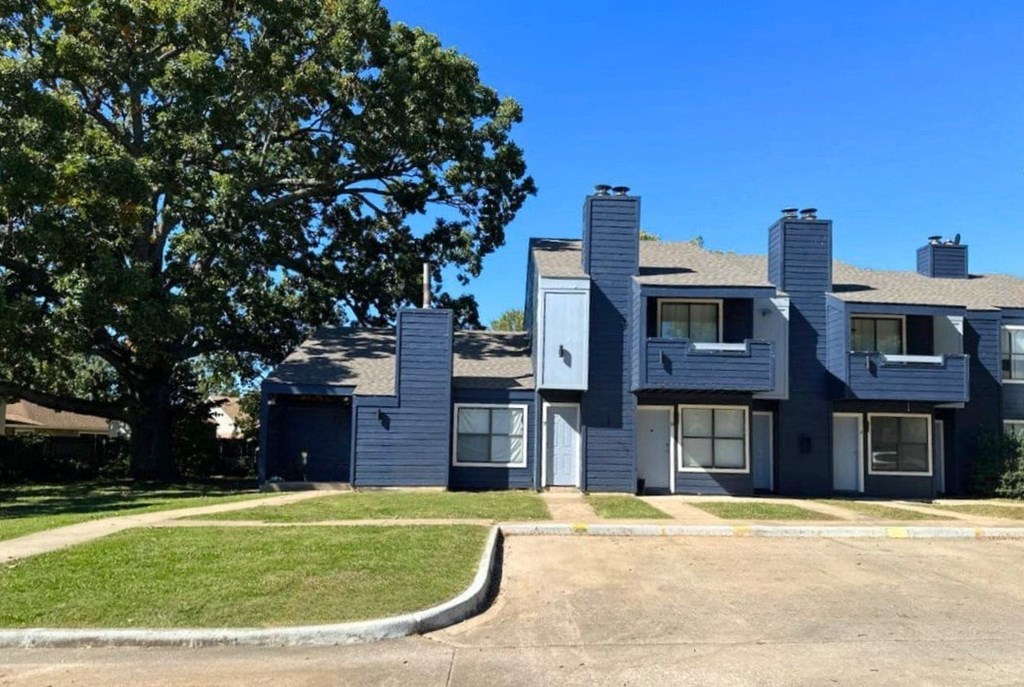 an apartment building with a large tree in front of it