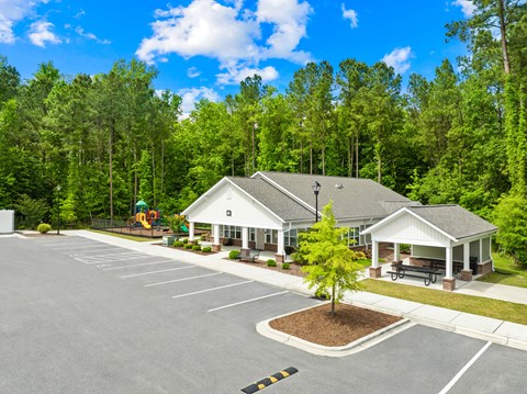 A parking lot with a building and a tree in the middle.