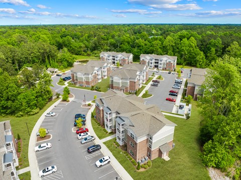 A large apartment complex with a parking lot in front.