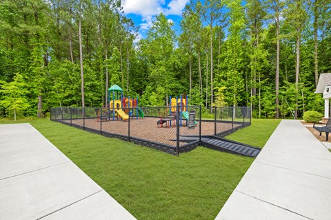 A playground with a swing set and slide in the middle of a grassy area.