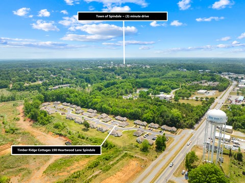 A bird's eye view of a residential area with a water tower and a road leading to a town.