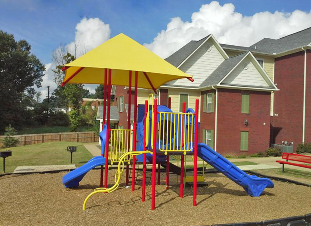a playground with a yellow umbrella and two benches
