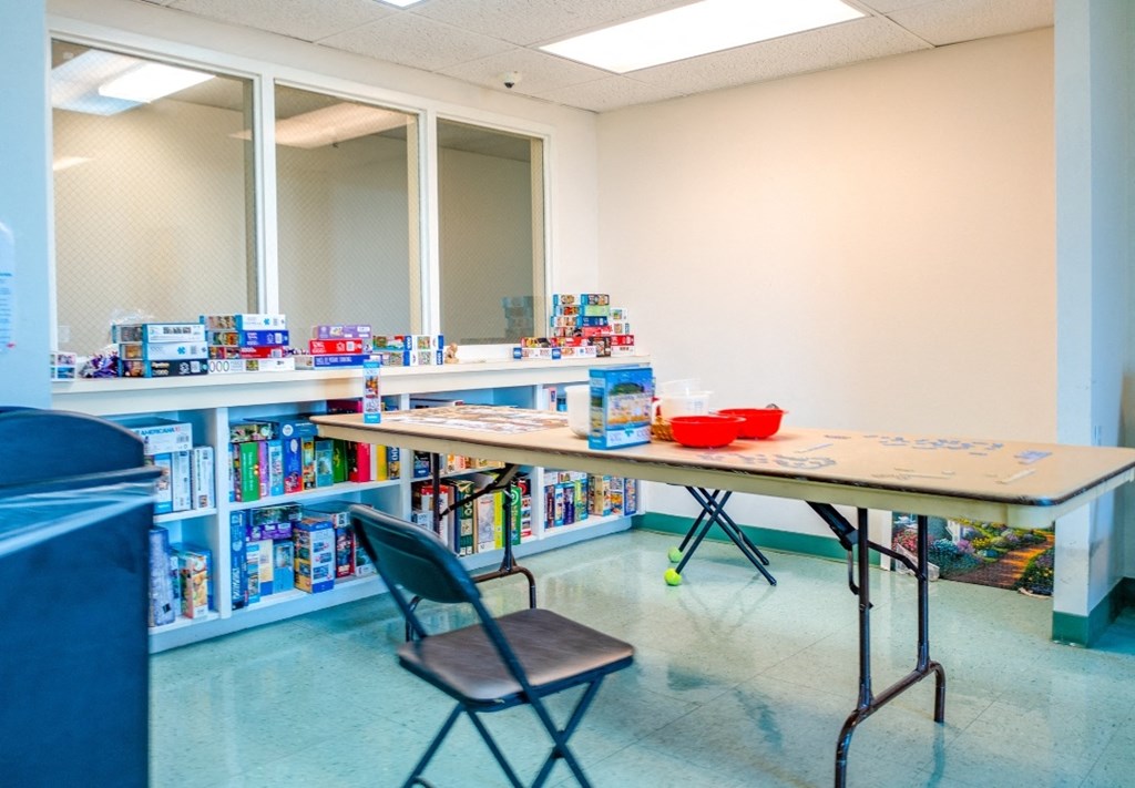 a room with a table and chair in front of a bookshelf with books