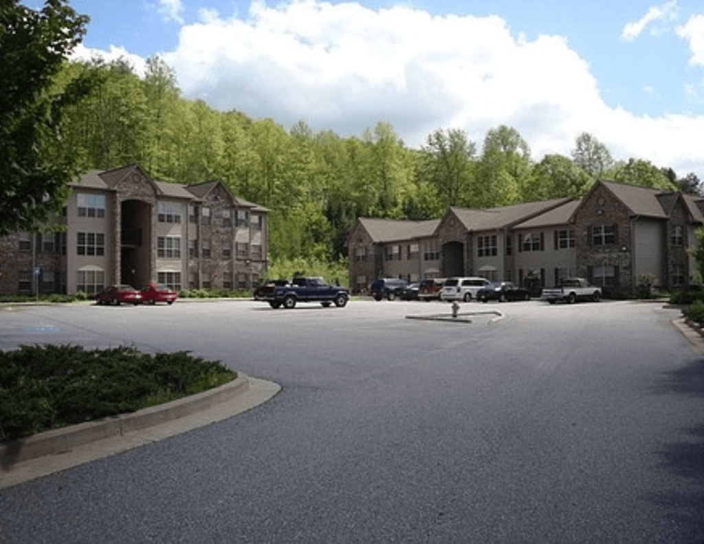 an image of an apartment complex with cars in a parking lot