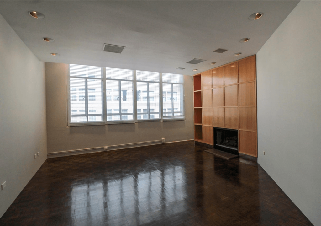 A large empty room with a fireplace and wooden paneling.
