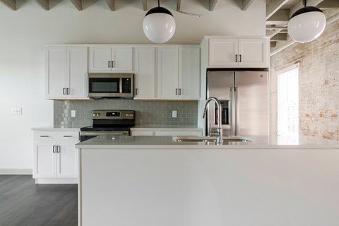 A kitchen with white cabinets and a white island.