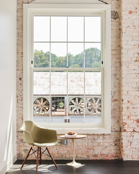 A white chair is in front of a window with a fan in the window.