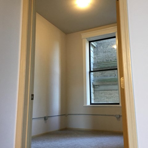 A room with a window and a white wall.
