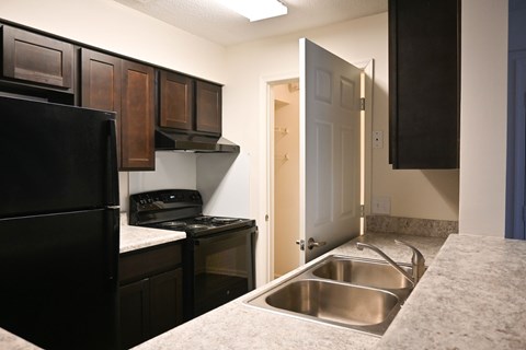 A kitchen with a black refrigerator and a stove top oven.