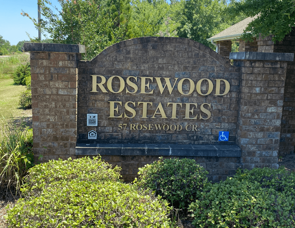 a sign for rosewood estates in front of trees and bushes