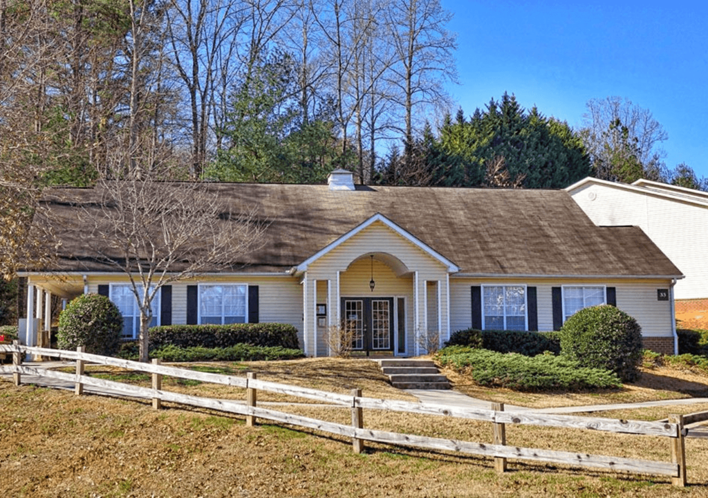 a white house with a brown roof and a white fence