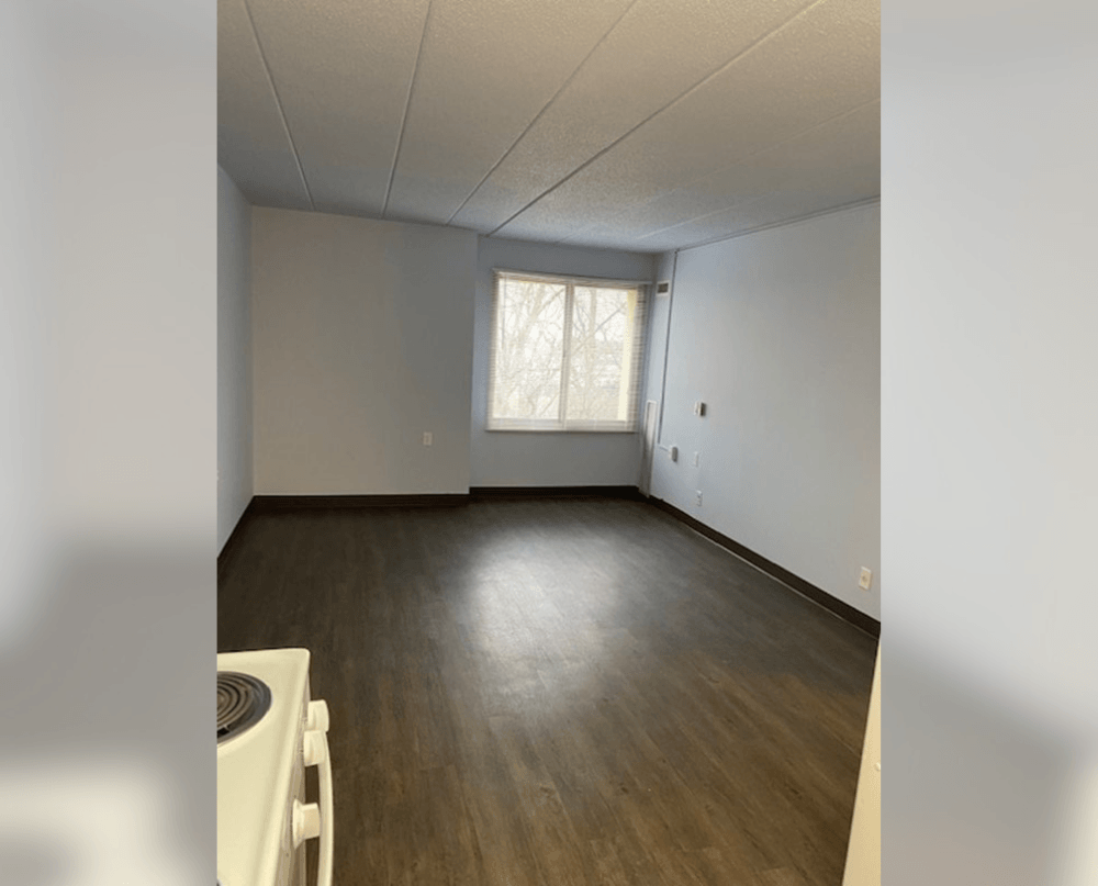 an empty living room with white walls and a window